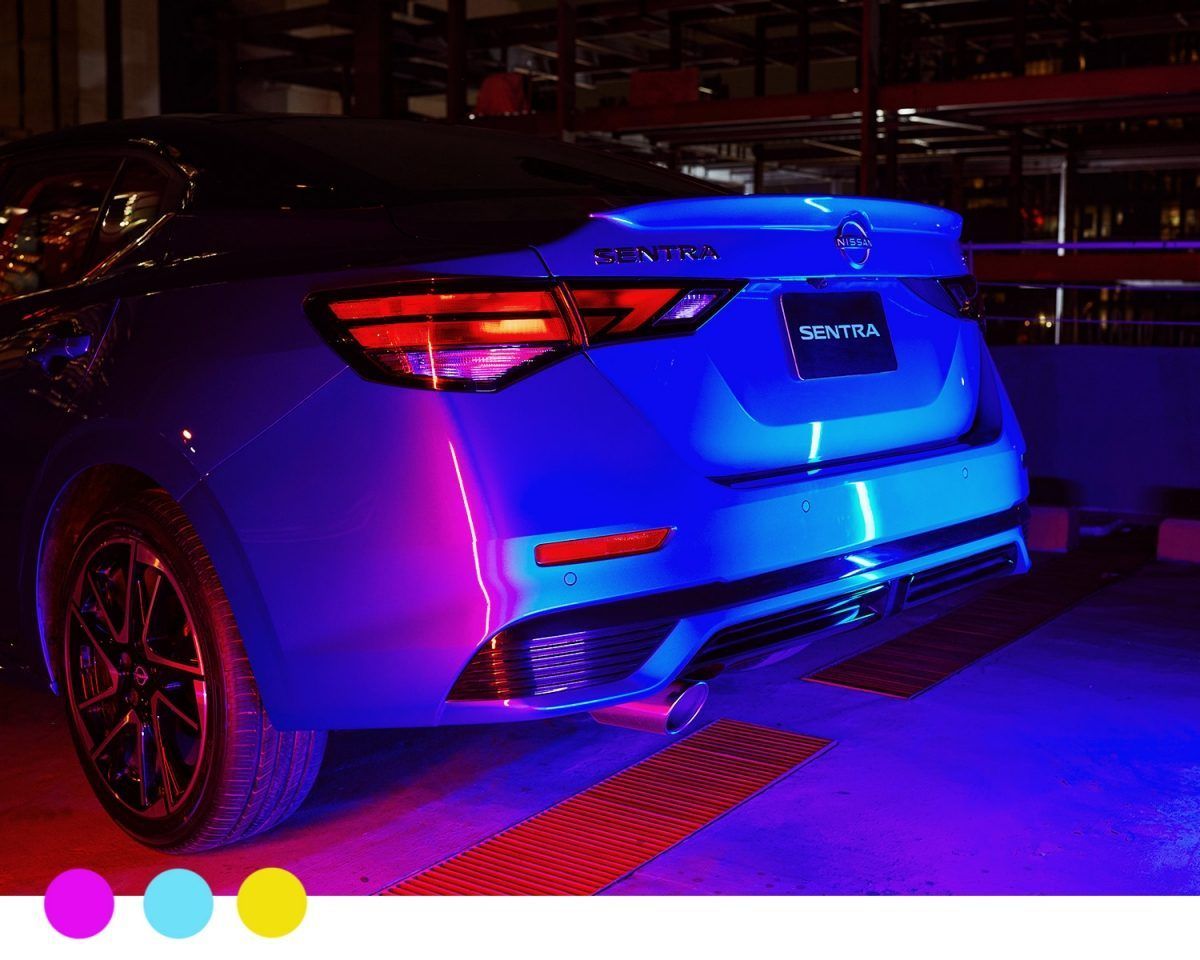 Coche deportivo azul con luces moradas en un garaje, visto desde atrás.