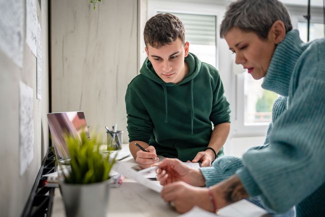 A woman is helping a young man with his homework.