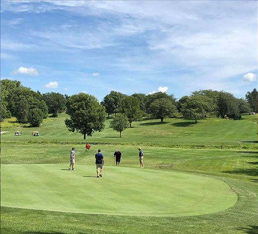 A group of men are posing for a picture on a golf course.