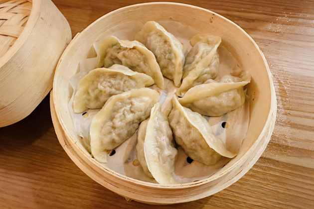 Steamed dumplings in a bamboo basket on a wooden table