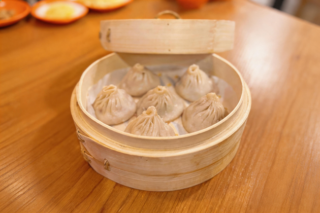 Steamed dumplings in a bamboo basket on a wooden table