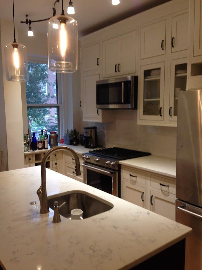 Modern kitchen with white cabinets, stainless steel appliances, and a central island with a sink.
