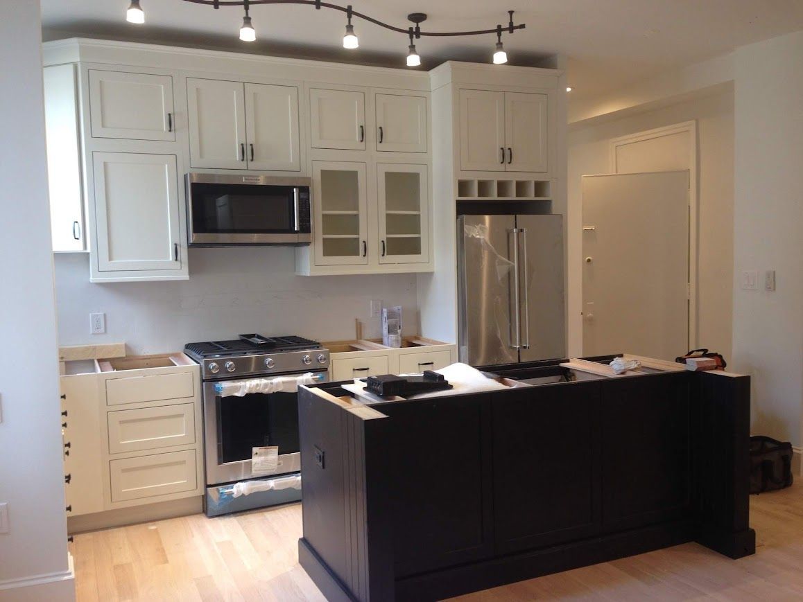 Kitchen with white cabinets, stainless steel appliances, black island.