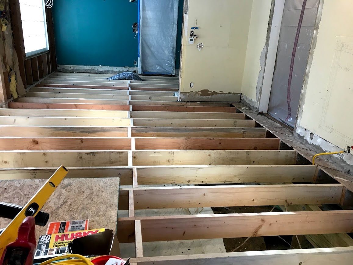 Interior renovation showing exposed floor joists. Turquoise wall in the background, tools in the foreground.