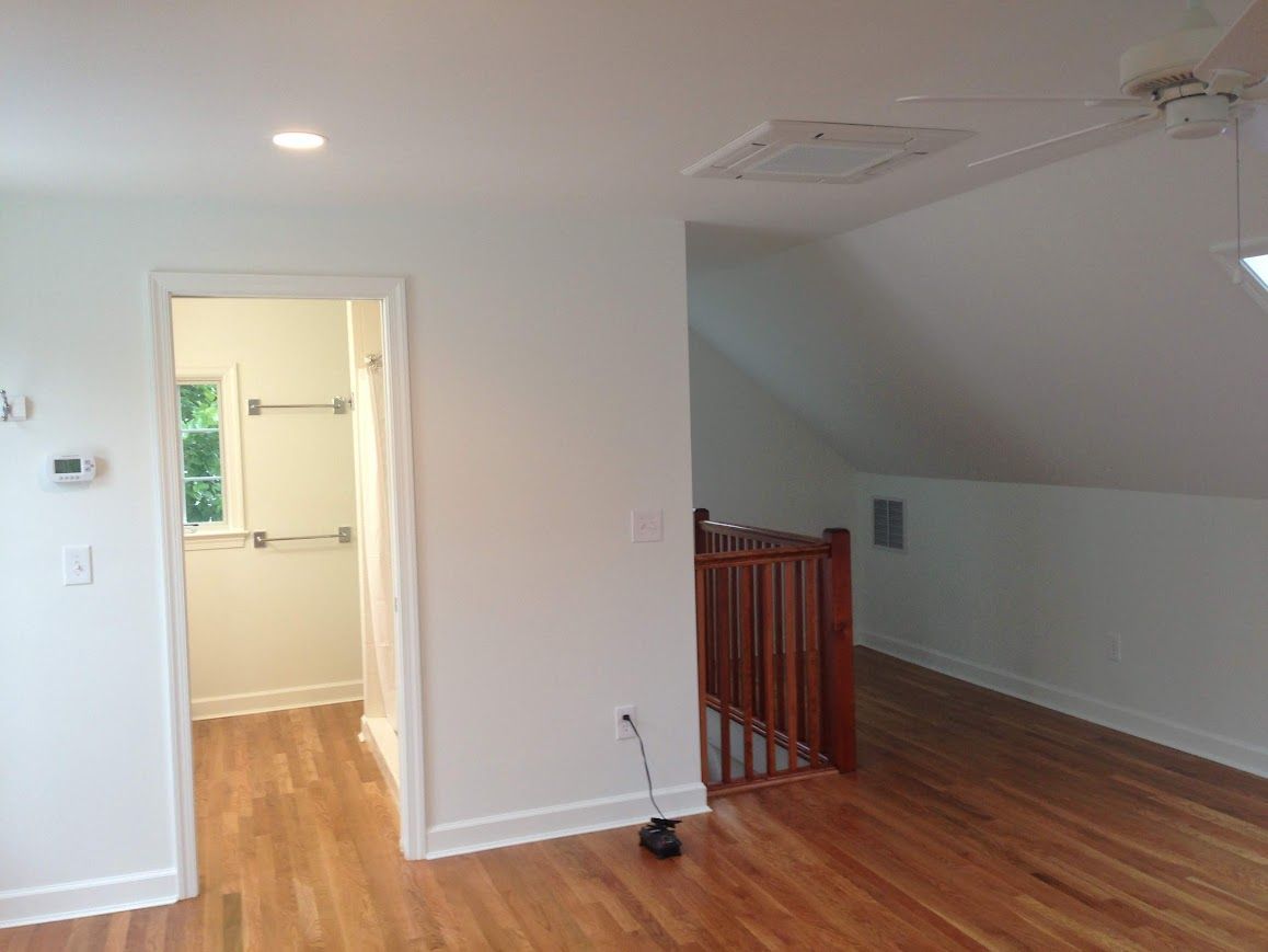 Interior view: Brightly lit room with hardwood floors, bathroom doorway, and a railing to an elevated space.