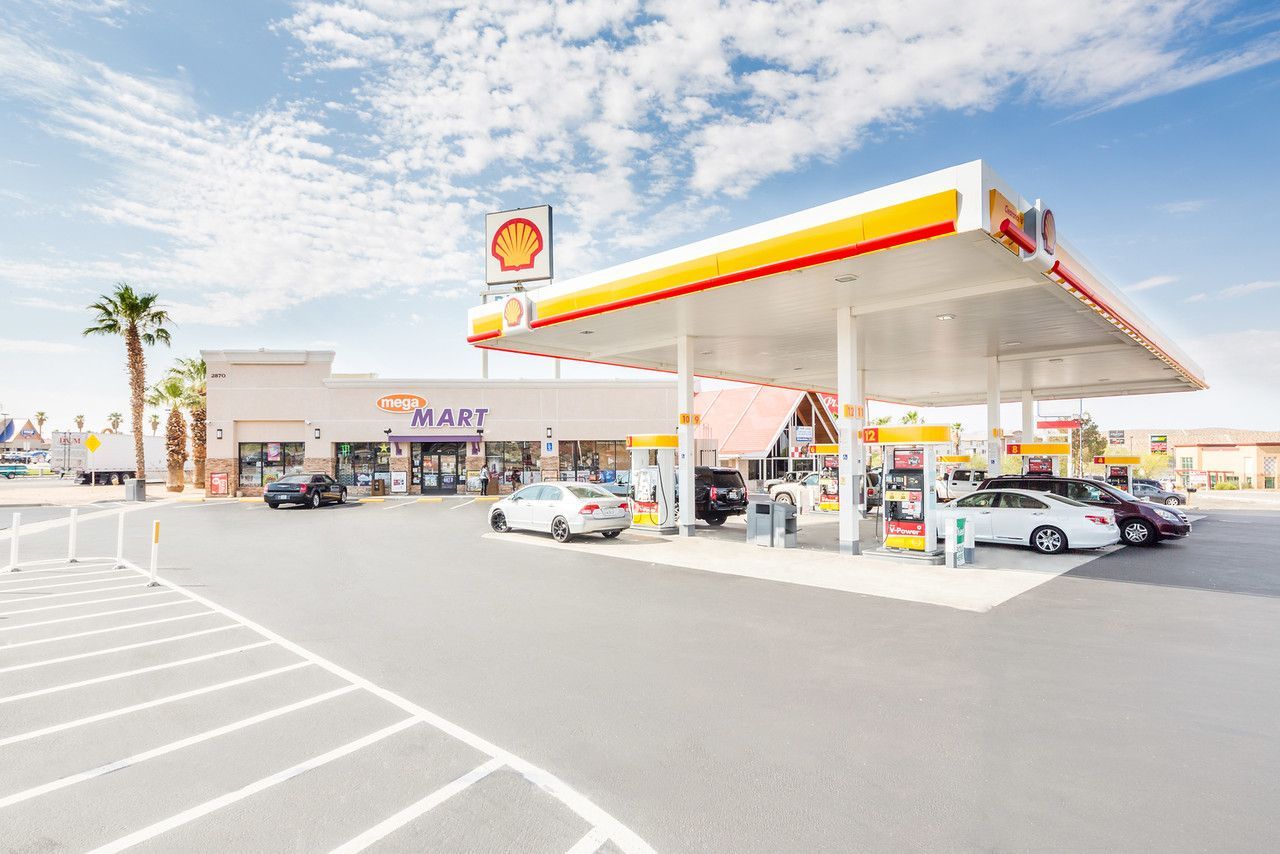 Shell gas station with cars under a yellow-and-red canopy on a sunny day