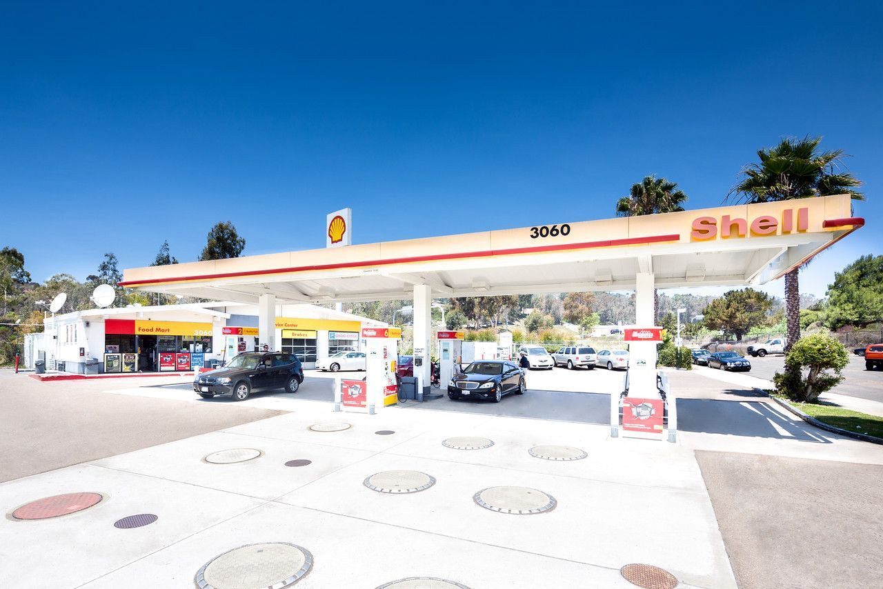 Shell gas station with several cars under a white canopy on a sunny day