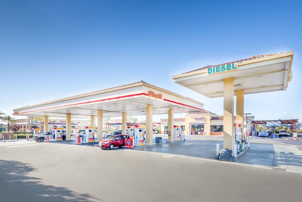 Shell gas station with cars fueling under a bright blue sky
