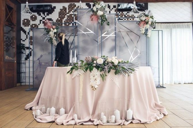 Decorated wedding reception table with pink drape, flowers, and a DJ setup behind it