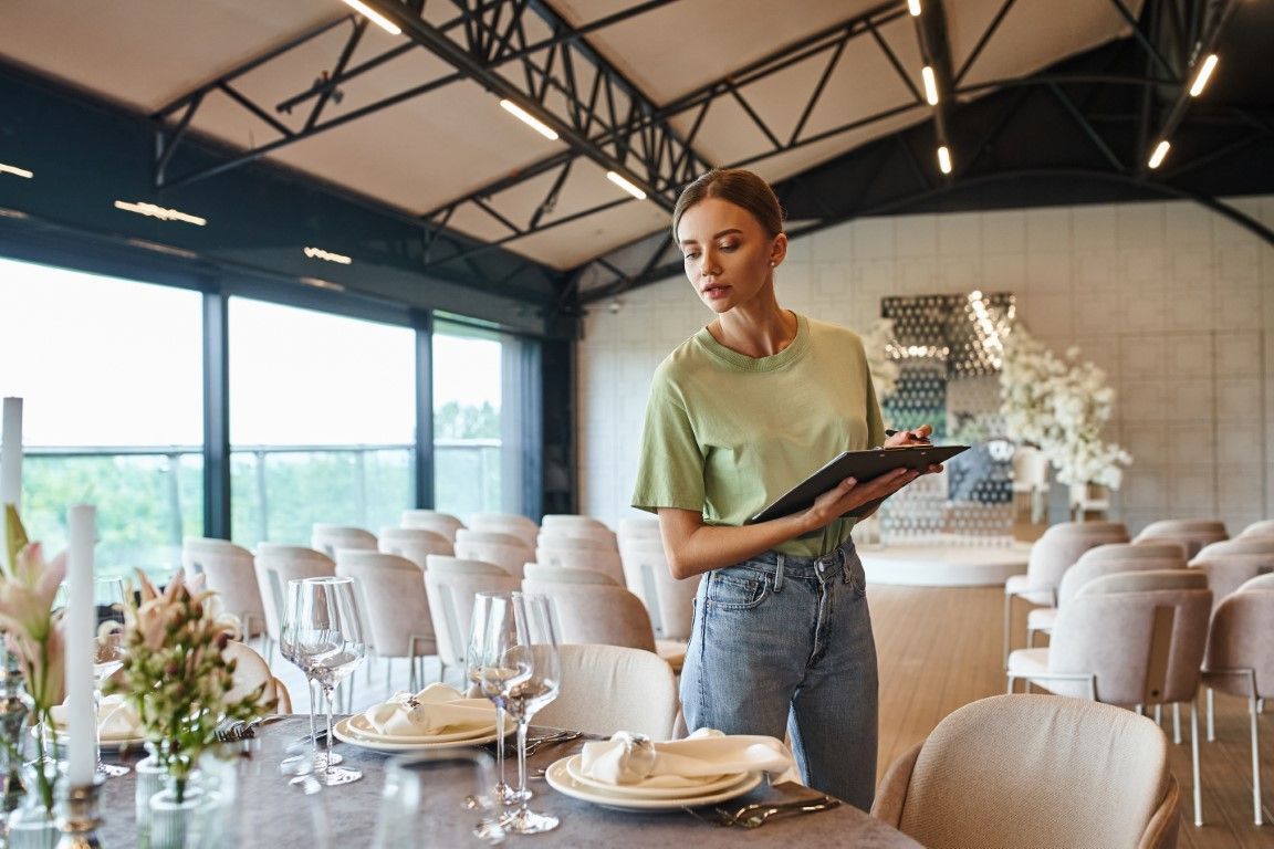 Server setting a table in a bright, modern banquet hall