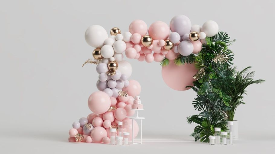 Pastel balloon arch with pink, white, and green decorations on a light background