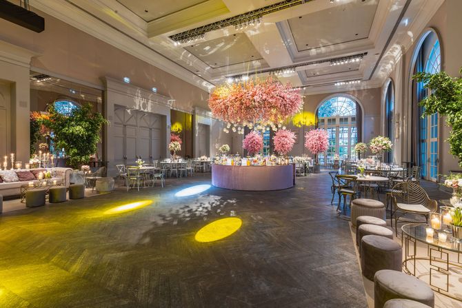 Elegant banquet hall with colorful floral centerpieces, chandeliers, and round tables set for an event