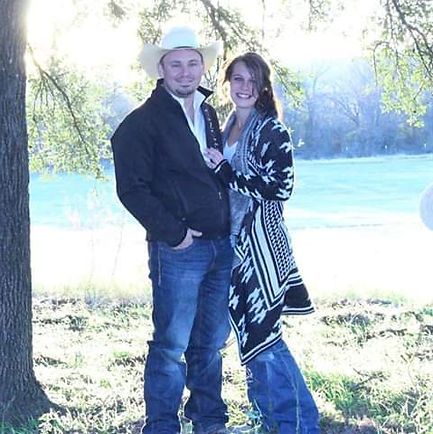 A man and a woman are posing for a picture in front of a tree.