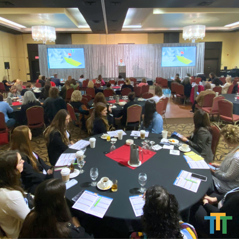 A group of people sitting around a table with a tt logo in the corner