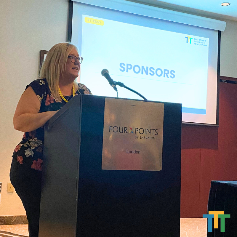 A woman stands at a podium that says sponsors on it