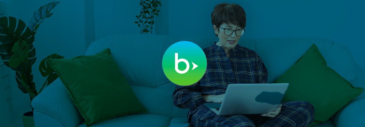 A man is sitting on a couch using a laptop computer.