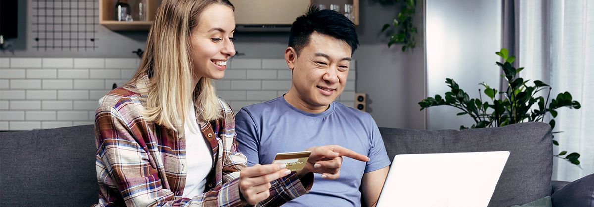 A man and a woman are sitting on a couch looking at a laptop.