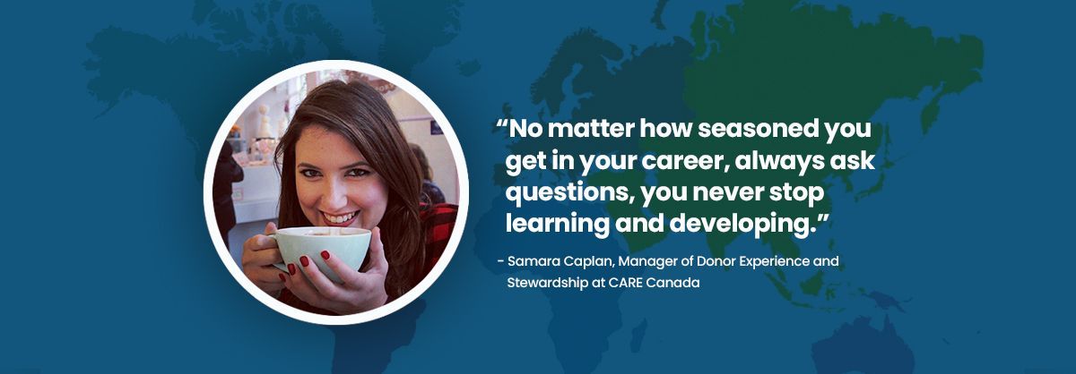 A woman is holding a cup of coffee in front of a map of the world.