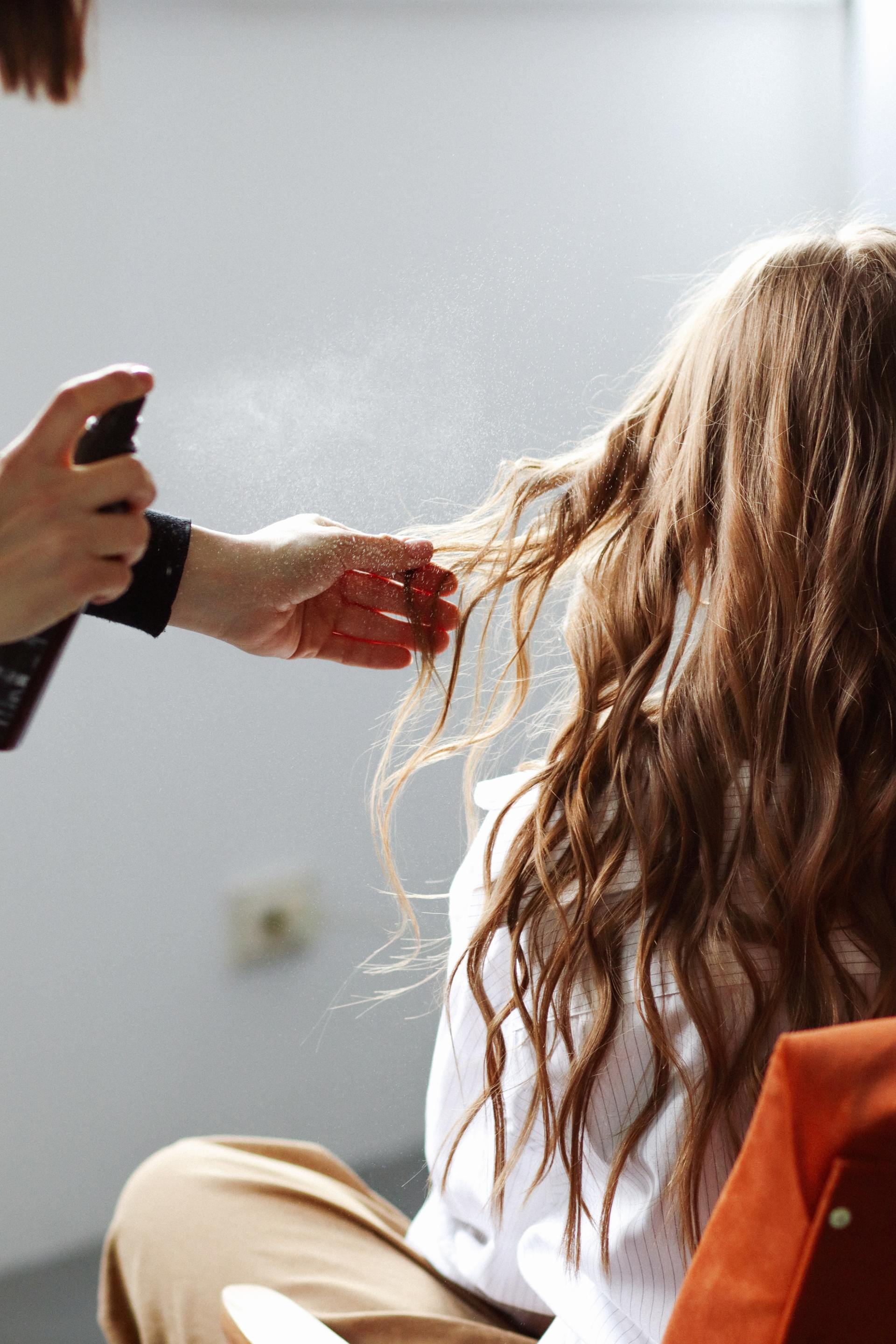 Une femme se fait vaporiser les cheveux par un coiffeur.