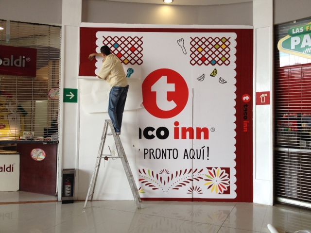 Hombre en una escalera instalando un letrero de tienda 