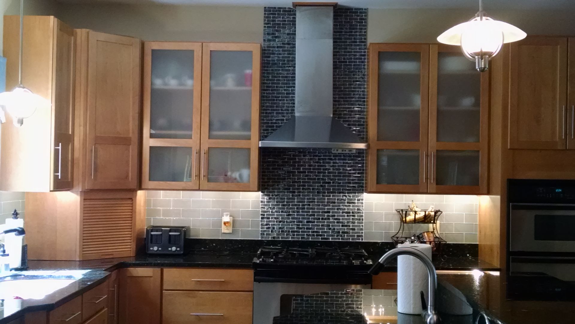A kitchen with wooden cabinets and black counter tops