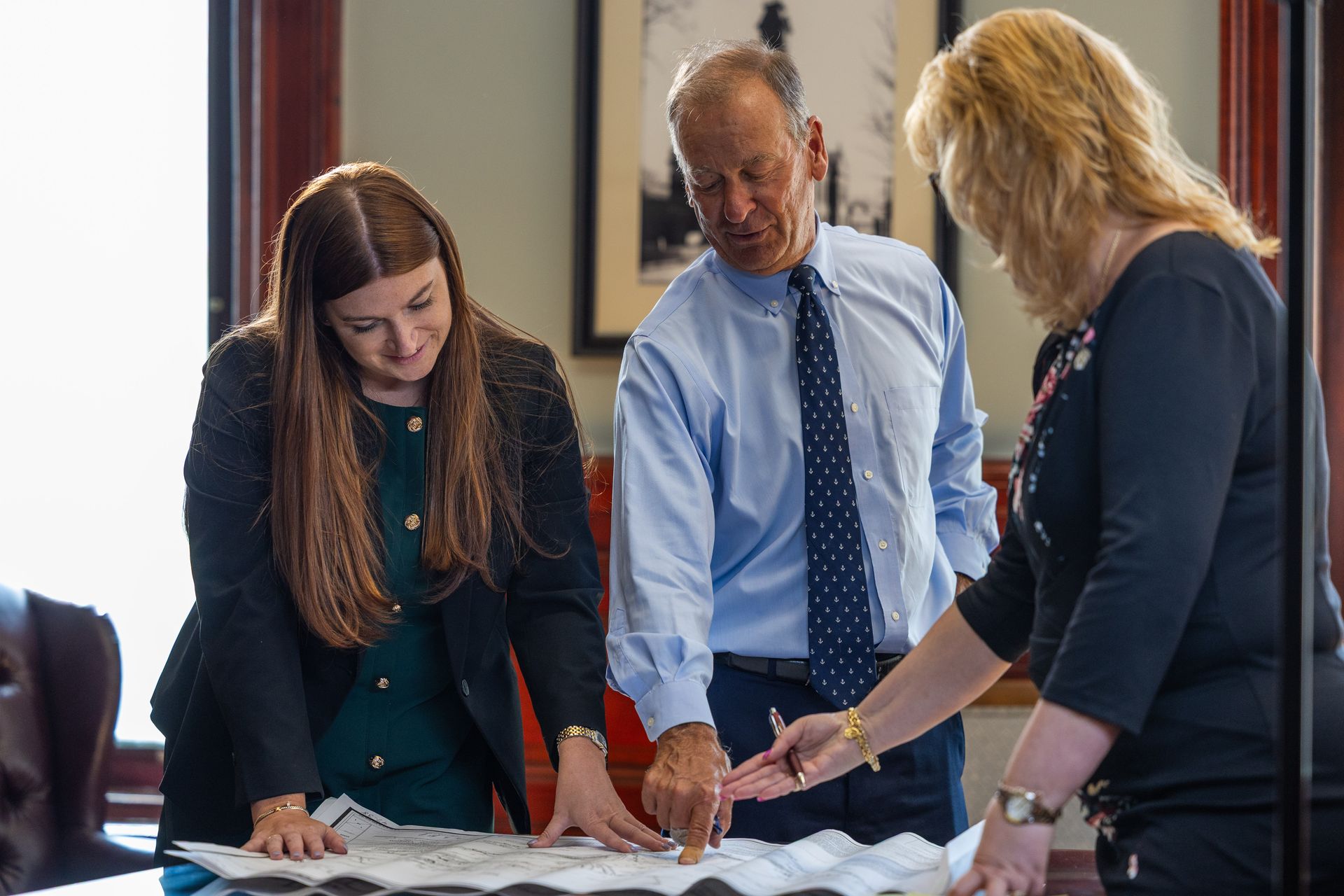Three people reviewing documents together at a table in a bright office
