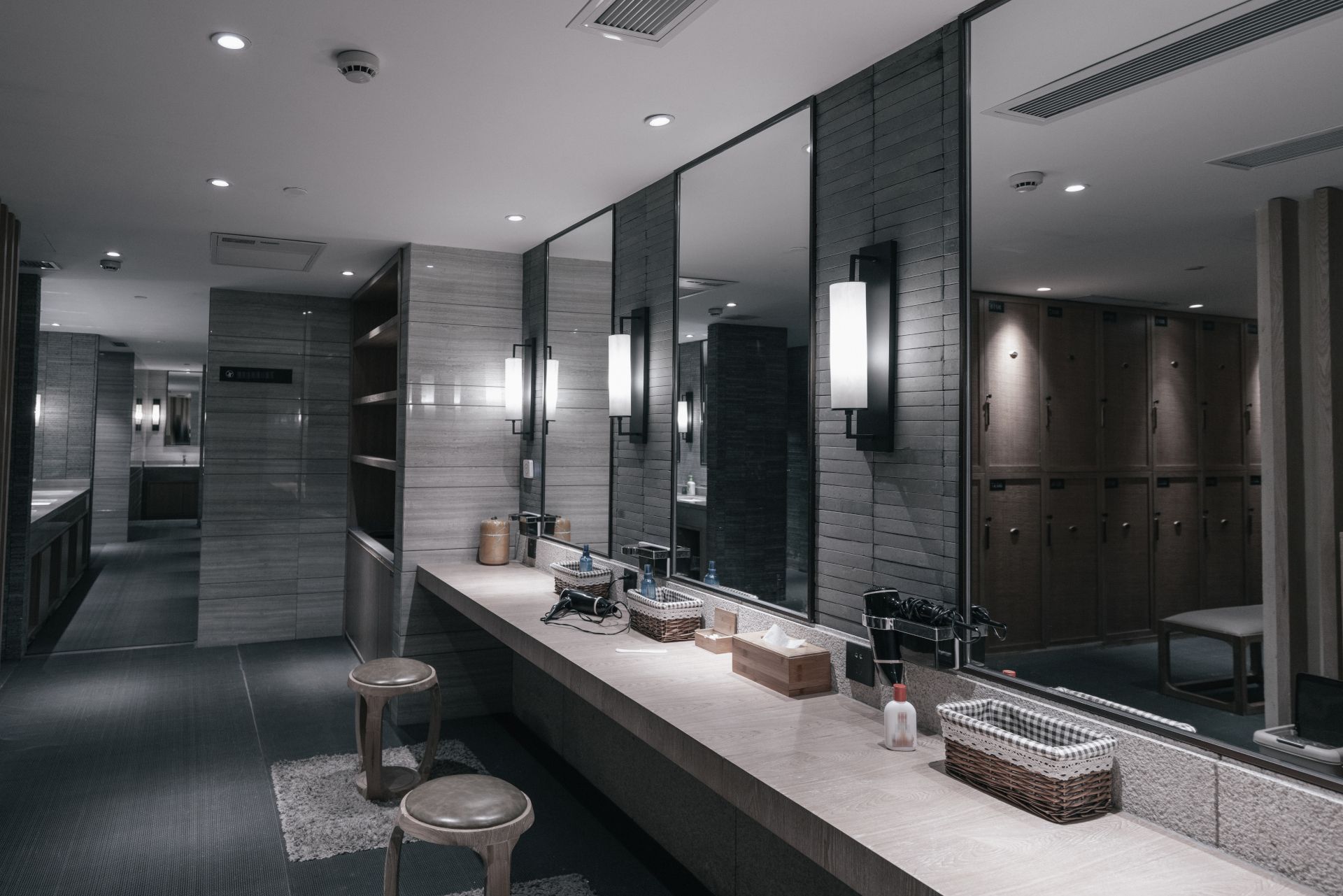 Modern bathroom with double sinks, mirrors, and wall sconces in a sleek gray interior