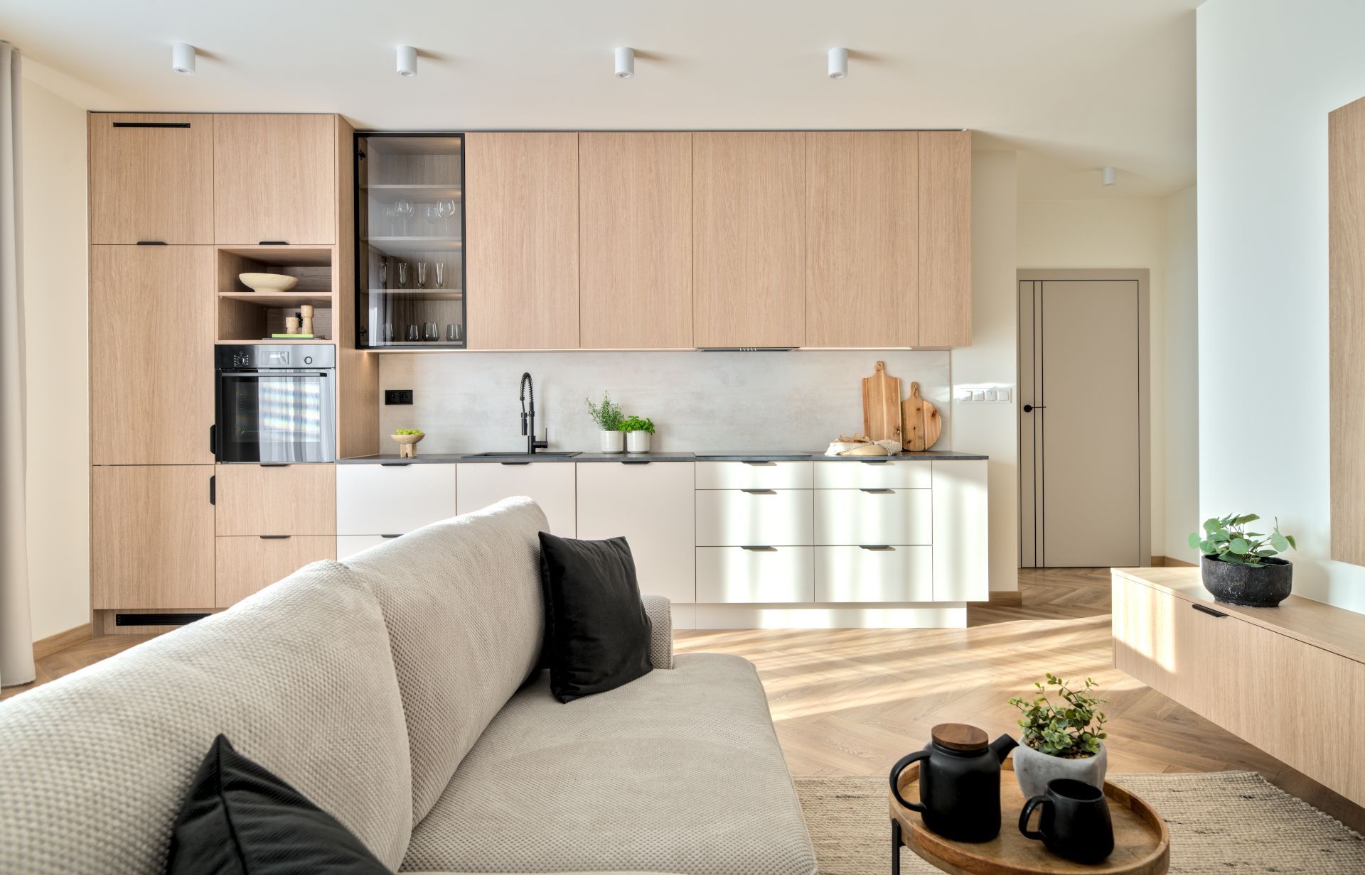 Bright modern living room with beige sofa, wooden cabinetry, and open kitchen area
