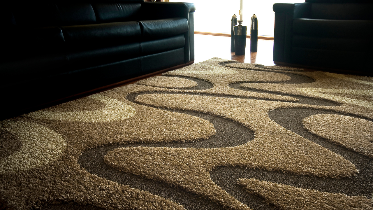 Brown and tan patterned rug with two black leather sofas in a living room.