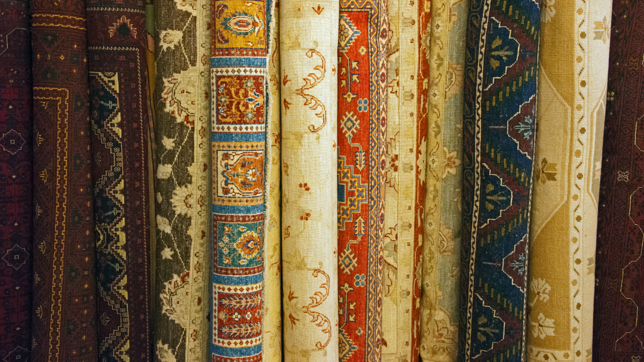Rolled up oriental rugs of various patterns and colors.