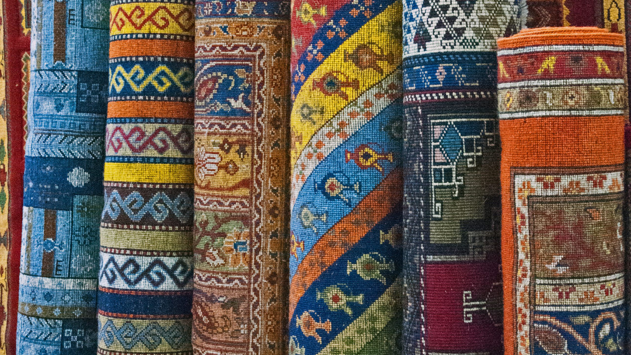 Rolled, colorful oriental rugs on display, featuring intricate patterns and designs.