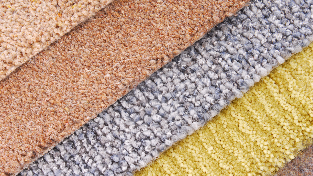 Close-up view of four carpet swatches: beige, rust, gray, and yellow, each with a different texture.