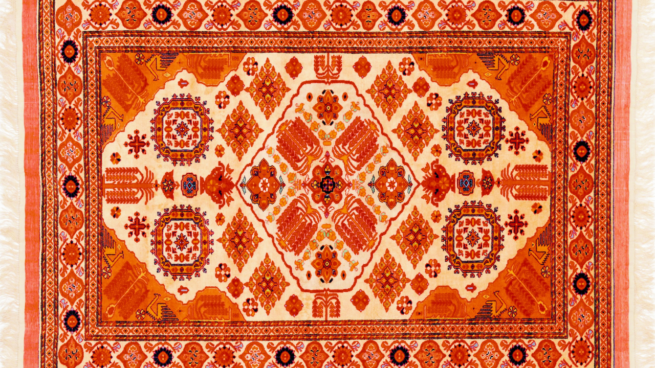 Orange and cream patterned oriental rug with geometric and floral designs.