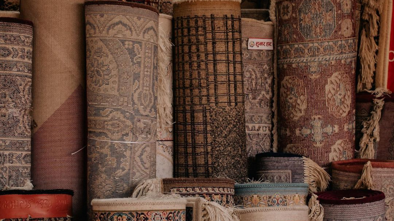 Rolled carpets of various patterns and colors stacked in a shop.