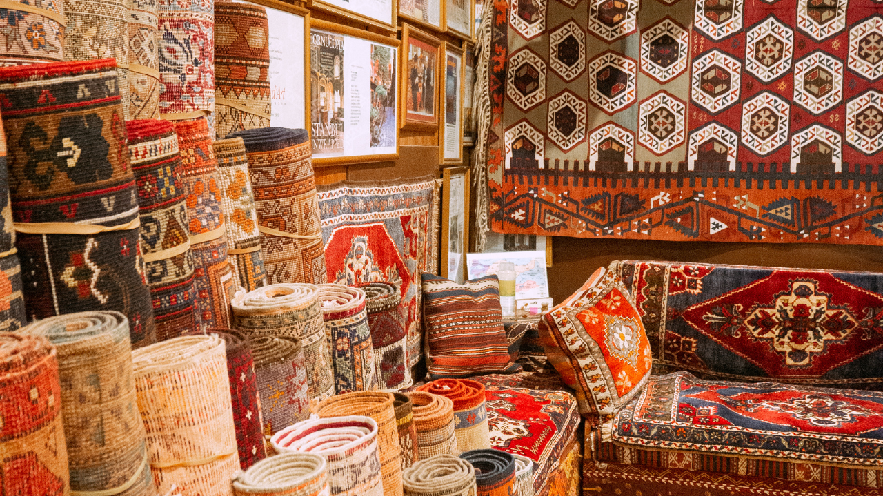 Stacks of colorful Persian rugs in a shop, showcasing various patterns and textures.