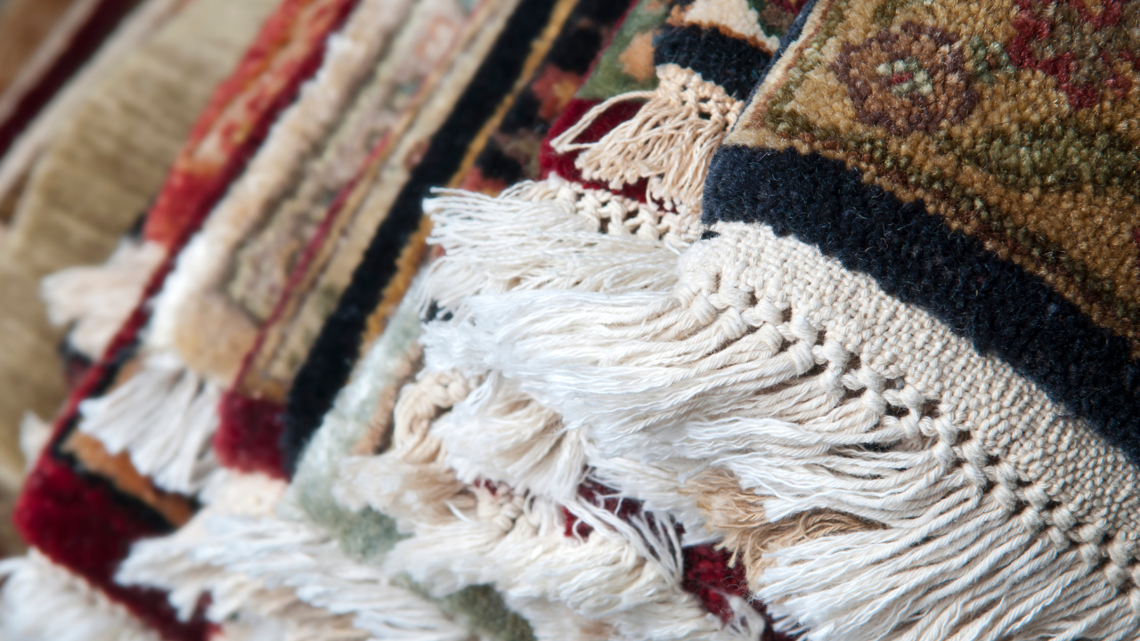 Pile of ornate rugs with white fringe.