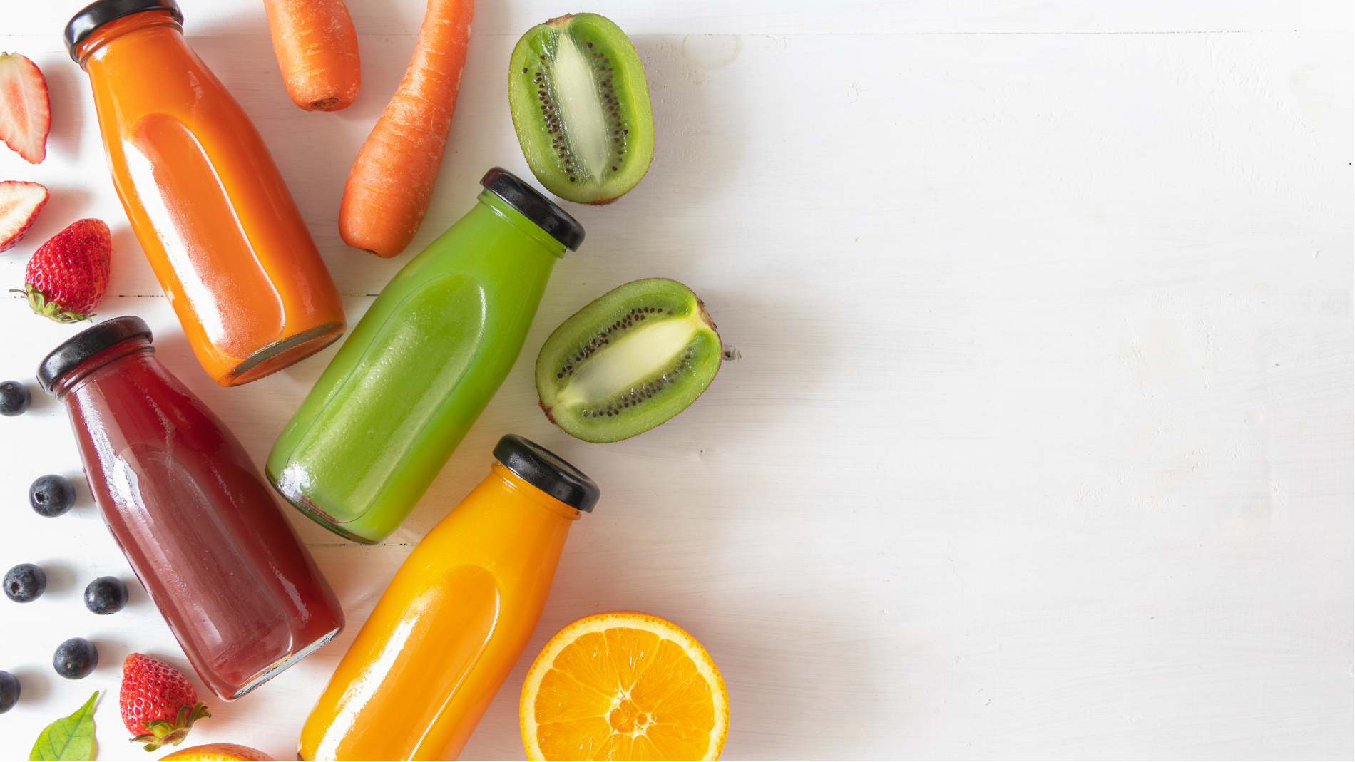 Assorted fresh fruit and vegetable juices with sliced kiwi and orange on a white background