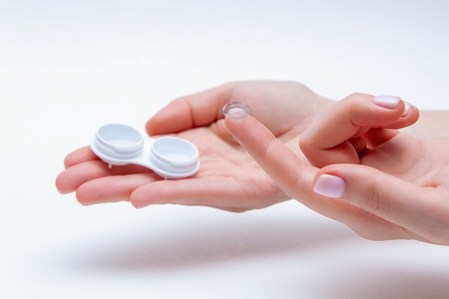 A woman is holding a contact lens case in her hand.