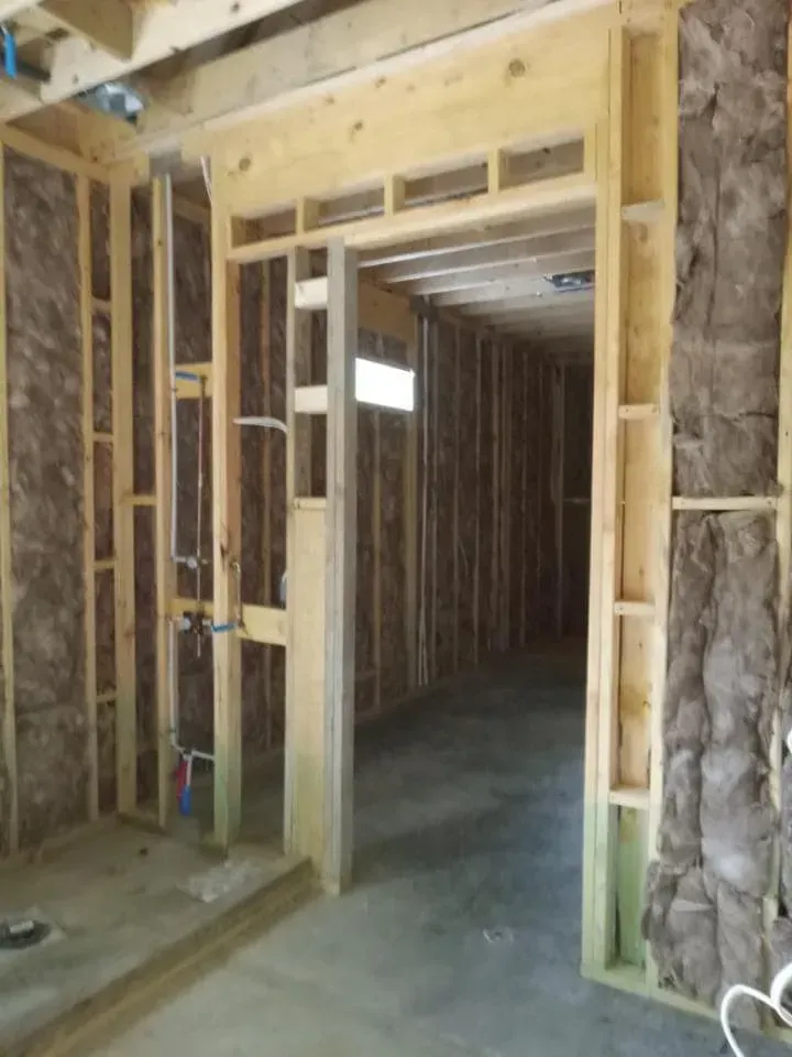 Framing for a doorway and walls in a building under construction, with exposed insulation.