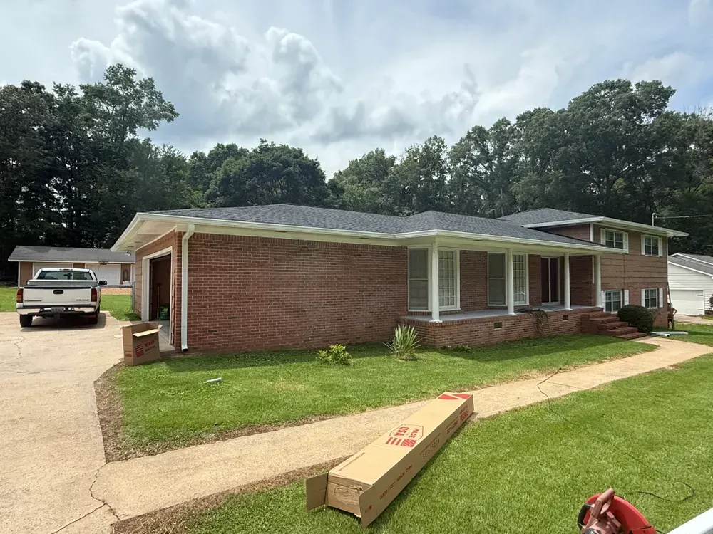Brick house with black roof, garage, and a truck parked outside.