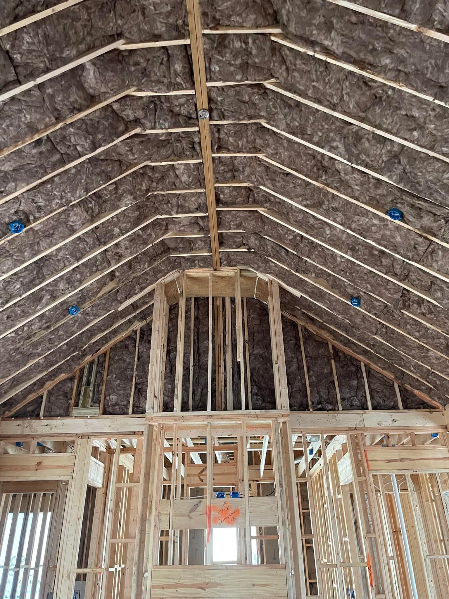 Interior view of a building under construction, showing wooden framing, insulation, and electrical boxes.