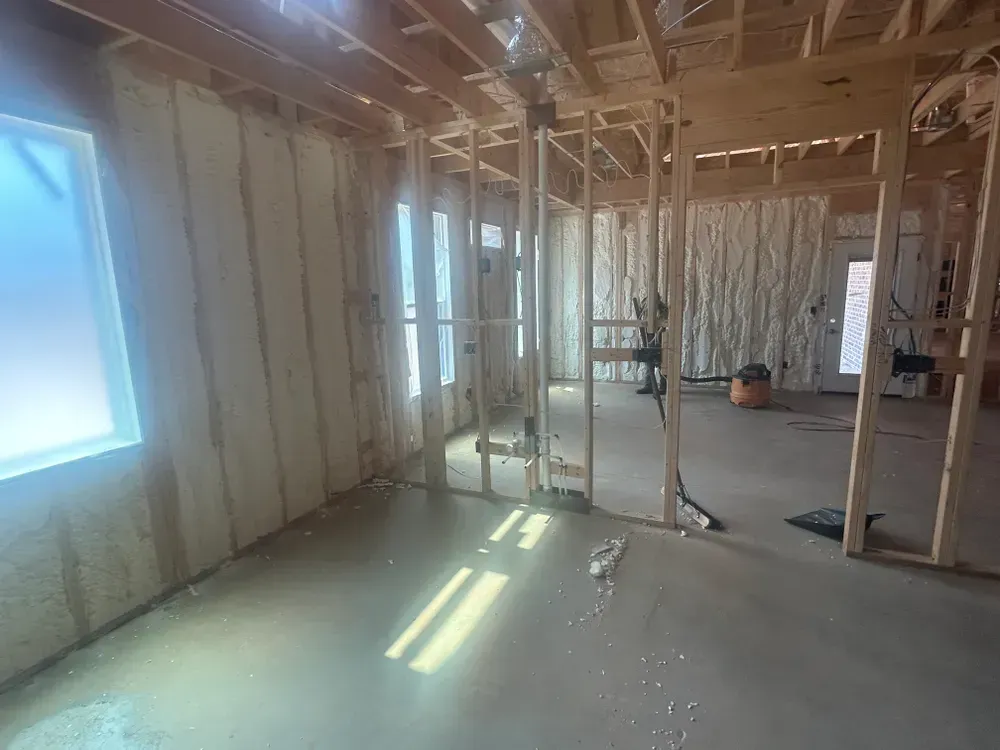 Interior of a house under construction; walls and ceiling frames are visible, spray foam insulation.