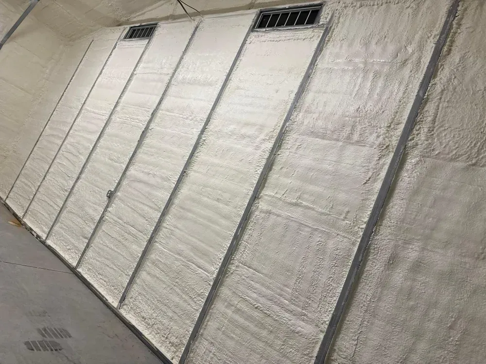 Insulated wall with metal studs and two vents. The wall is slanted with textured, white insulation.