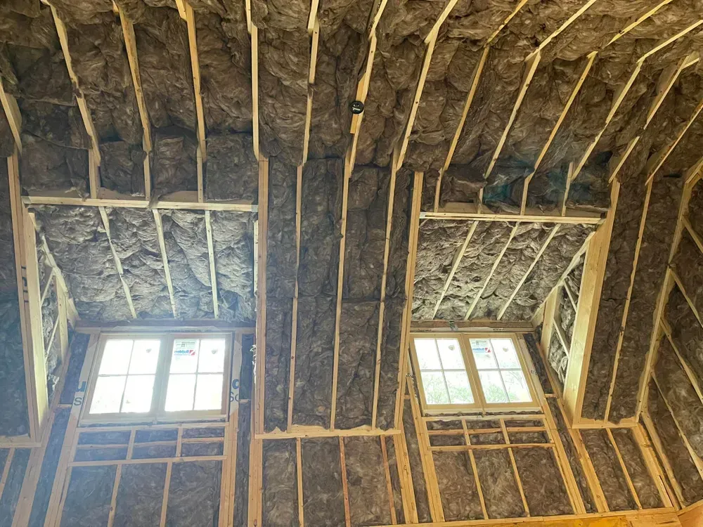 Interior view of a building under construction, featuring windows framed by wooden beams and insulation.