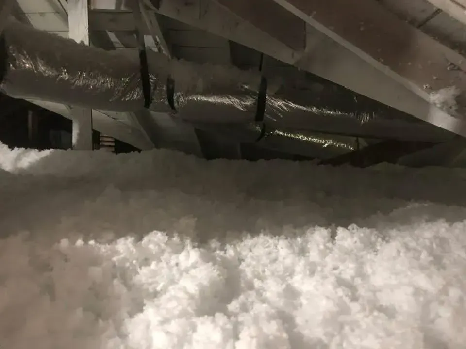 Attic with thick white insulation and insulated ductwork.