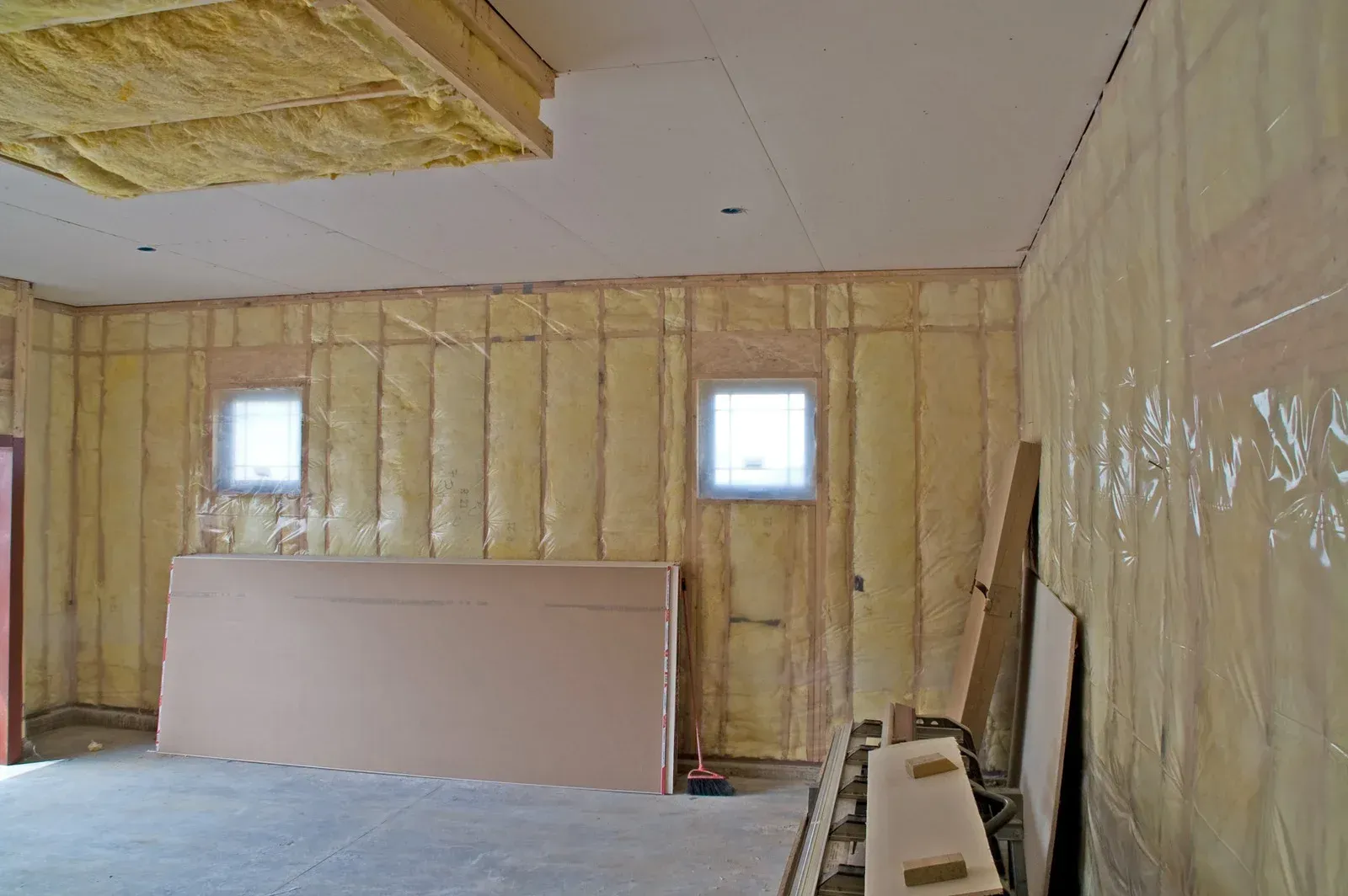 Interior room under construction, walls and ceiling insulated with yellow batting.
