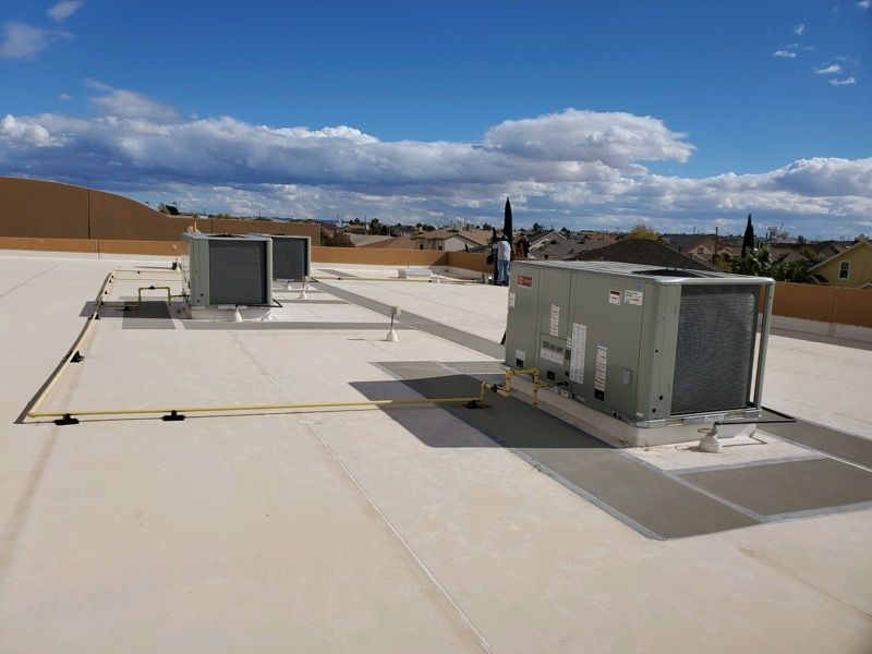 Rooftop HVAC units on a flat white roof under a blue sky