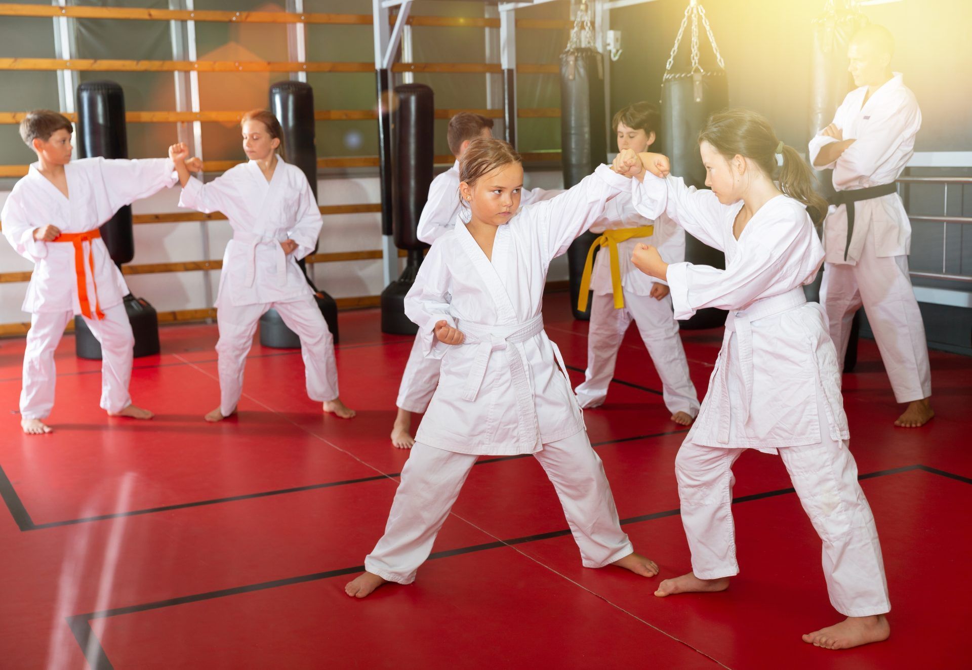 Children practicing martial arts in white gis on red mats in a dojo