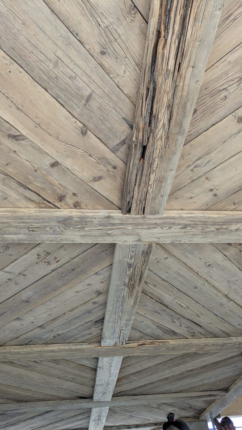 Soffitto in legno con travi disposte in diagonale, invecchiato e grigio.