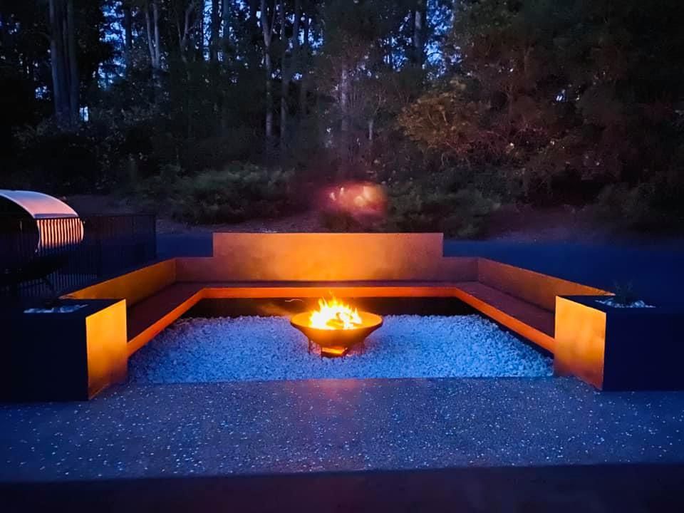 Fire Pit at Night, Surrounded by Seating and Blue Pebbles — Wal's Concreting Service Pty Ltd in North Casino, NSW